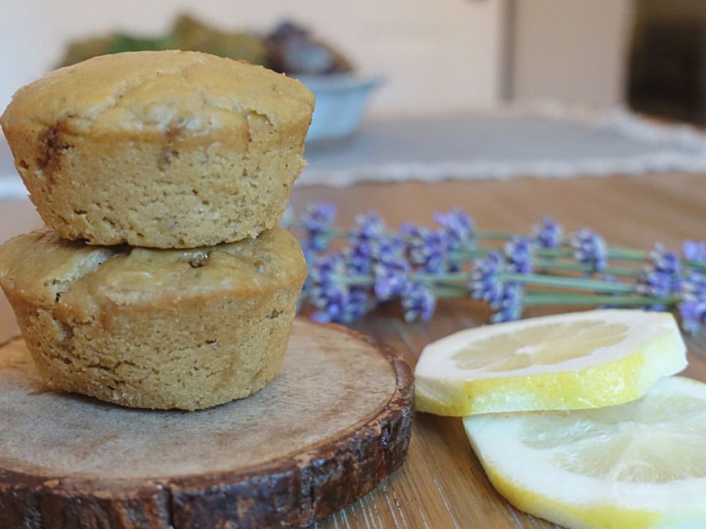 lemon lavender sourdough discard muffins with lemons and lavender on the side of two muffins stacked on top each other