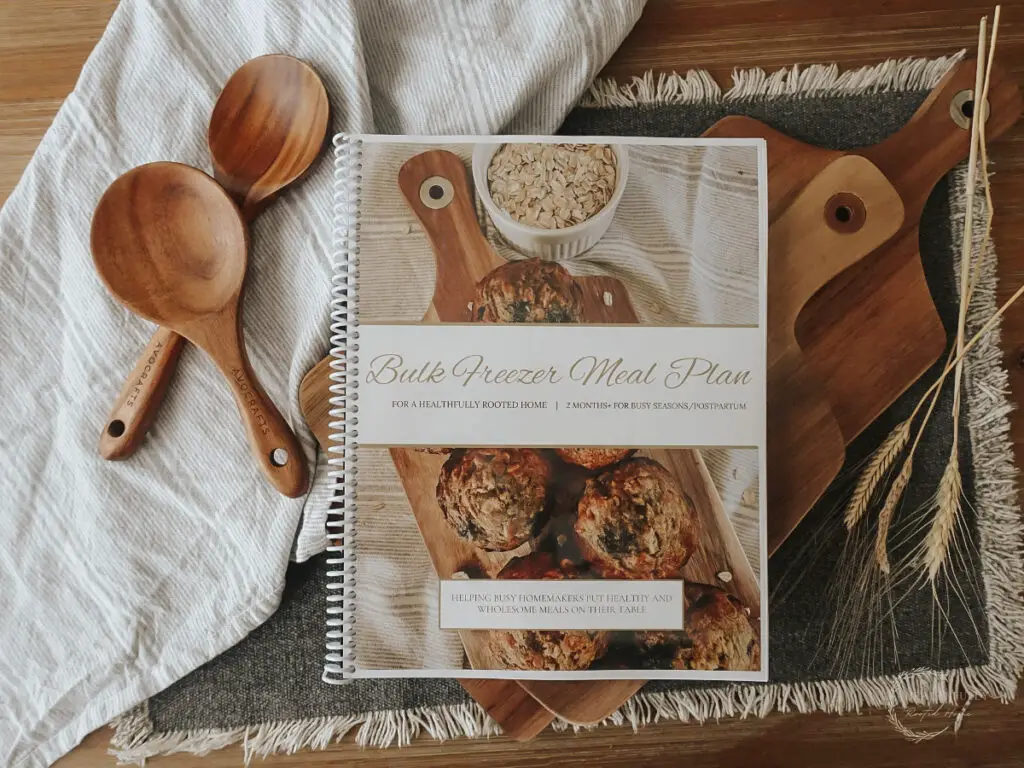 freezer meal prep meal plan in a spiral bound notebook with wooden spoons on the side