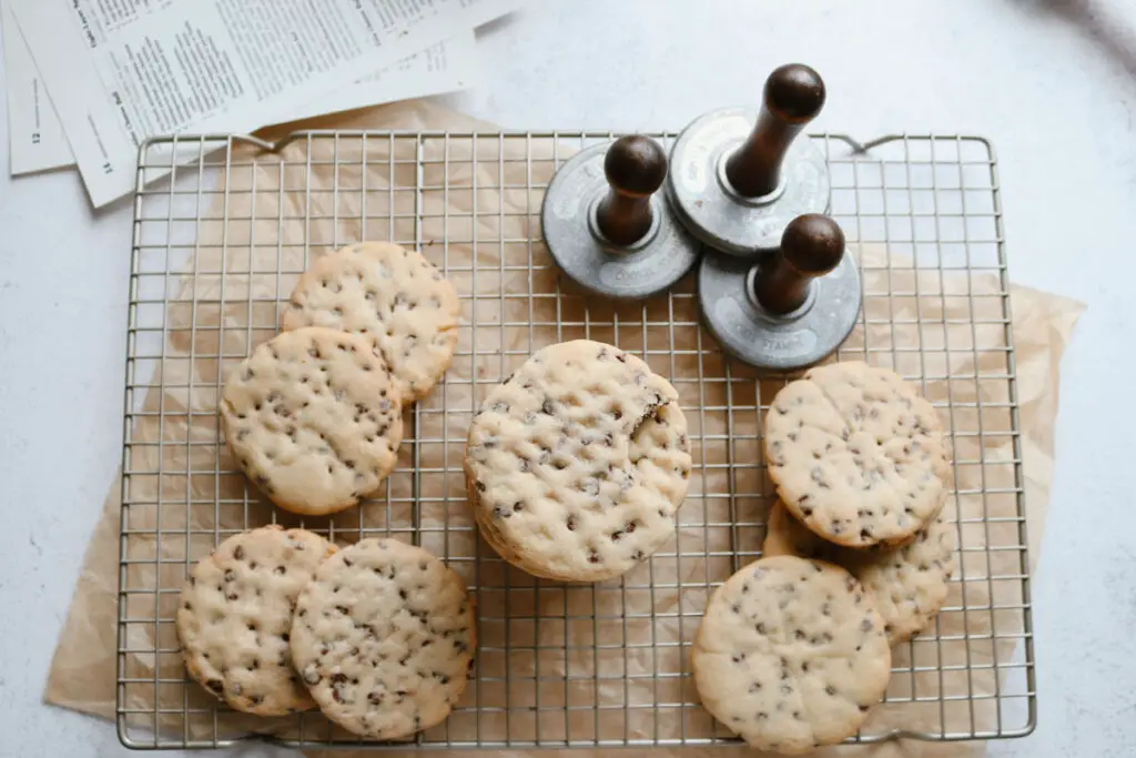 chocolate chip sugar cookies with cookie stamps on a cooling rack with recipes next to it
