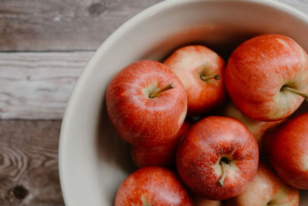 large bowl of red apples with a wooden background