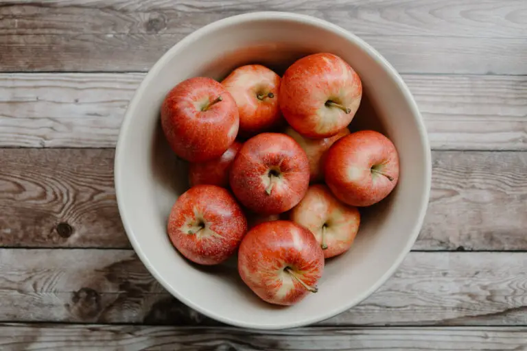 bowl of red apples on a wooden table