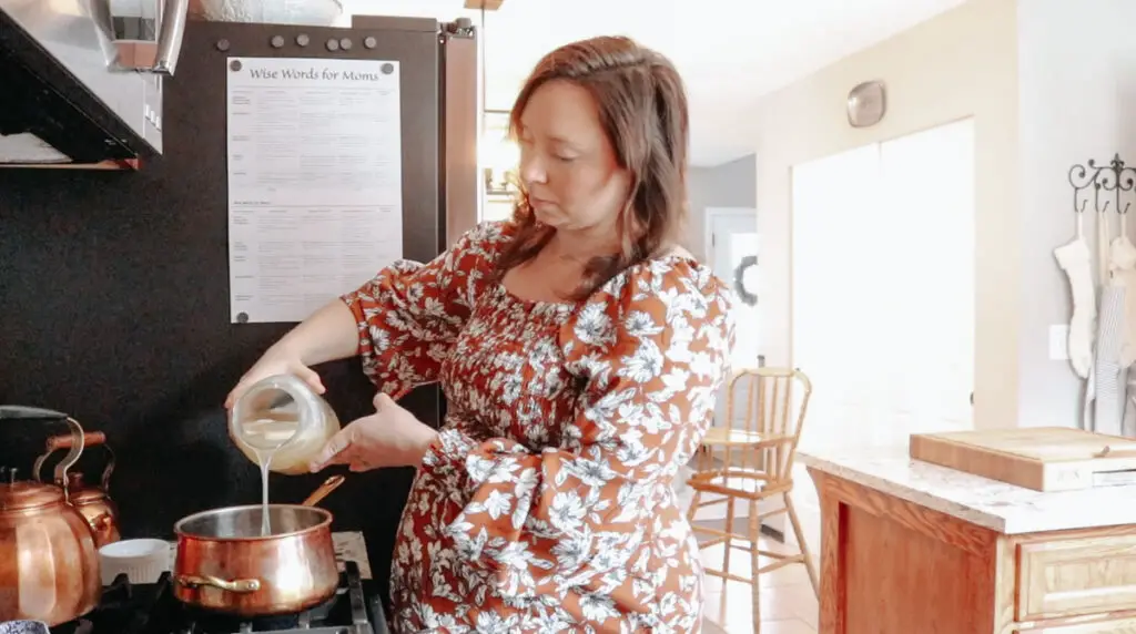 christian homemaker in a dress making bone broth in a copper pot