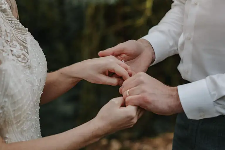 husband and wife holding hands on wedding day in a forest